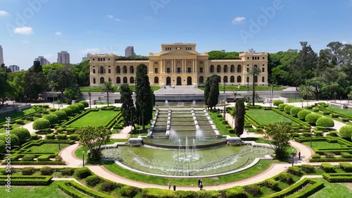 SÃO PAULO, BRASIL - AGOSTO DE 2026: Vista aérea ampla do histórico Museu do Ipiranga, com seus jardins simétricos, fontes de água e o horizonte denso da cidade ao fundo sob a luz do dia