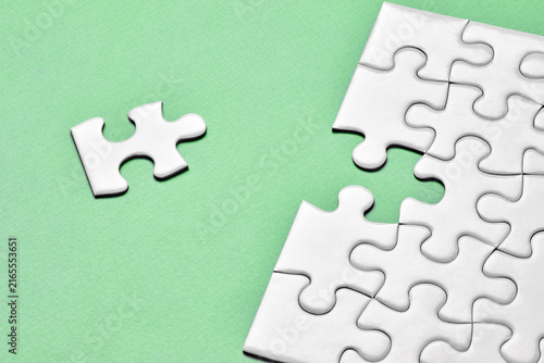 Incomplete jigsaw puzzle with missing piece on green background