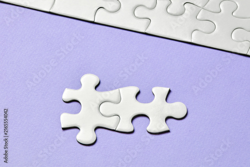 Two interlocking puzzle pieces on purple background