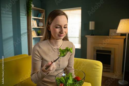 Bild auf Leinwand Young woman sitting on a yellow sofa in her living room, feeling disgusted by th