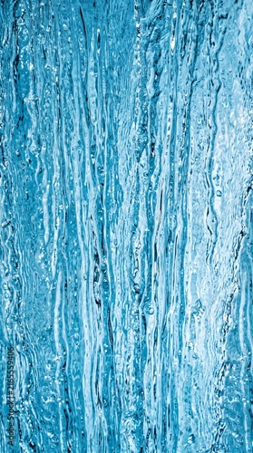 Blue flowing water streams abstract vertical texture background with droplets