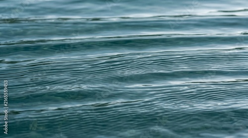 Dark teal water surface with parallel ripple waves abstract nature background