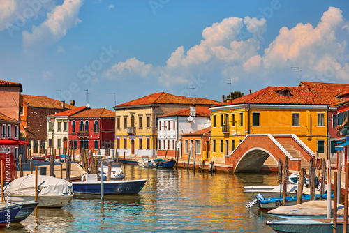 Island Murano in Venice Italy. View on canal with boats and motorboats on water. Summer day picturesque landscape.