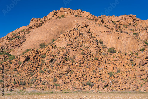 Obraz na plátně Massive granite rock formations and scattered desert boulders stand under a clear sky at Spitzkoppe in the Erongo region of Namibia
