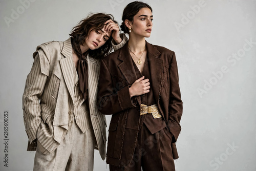 Elegant fashion models in oversized suits, stylish women in brown and beige tailoring, high-end editorial portrait for apparel branding