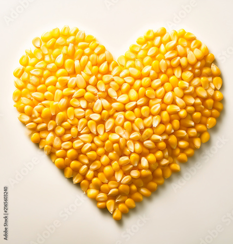 A pile of yellow corn kernels forms the shape of a heart.