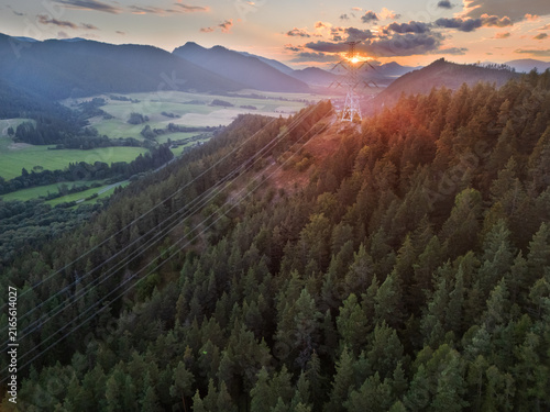 Aerial view of mountains over Svarin on Cierny Vah valley with a high-voltage power line crossing dense pine forest during sunset in Kralova Lehota, Zilinsky kraj, Slovakia.