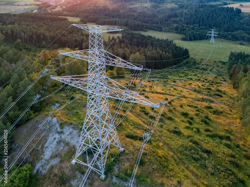Aerial view of a high-voltage electricity pylon on a grassy hillside surrounded by dense pine forests in the Cierny Vah valley near Kralova Lehota, Zilinsky kraj, Slovakia.