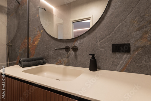 Cuadro en lienzo Bathroom vanity shown with warm linear ceiling glow appearing in the mirror above a wide frontal basin, with warm indirect interior lighting