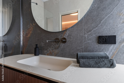 Foto Bathroom vanity styling presented with folded towels dominating the right foreground opposite a black soap, with warm indirect ceiling light