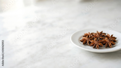 Dried Star Anise Spices Arranged on a Small White Plate Resting on a Clean Bright Marble Kitchen Countertop Background