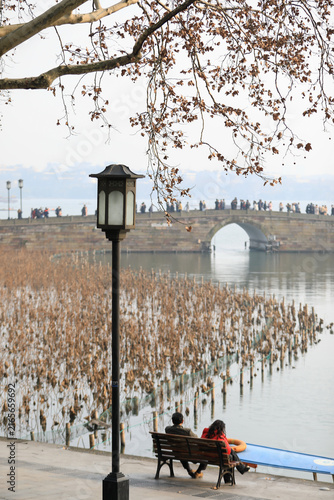 Obraz na płótnie Autumn at West Lake, Hangzhou, China with stone bridge, lakeside lamp, and visit