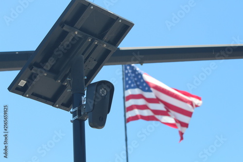 Cuadro en lienzo Flock camera monitoring a parking lot as an american flag waves in the background