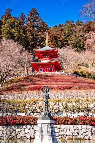 Red pagoda and stone fountain at Ryuanji Temple near Minoh Waterfall attract visitors and local people in Osaka, Japan