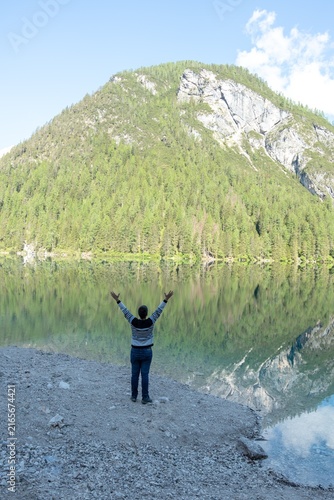 Fotografie Person standing at mountain lake reflecting nature and freedom