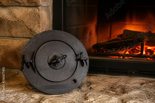 Foto Cast iron fireplace damper plate on textured stone with warm ember glow, cozy he