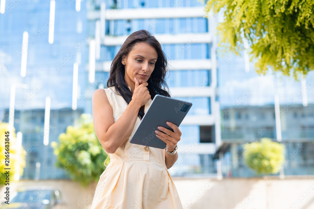 Fototapeta premium Businesswoman thinking while using digital tablet outdoors