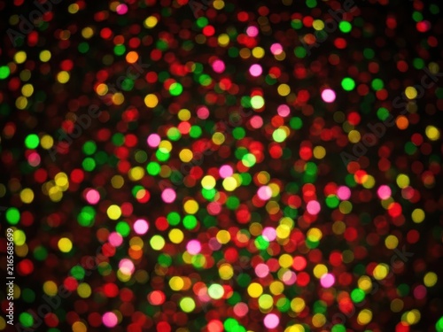 Abstract background with blurred bokeh lights in red, green, and yellow colors on a dark surface