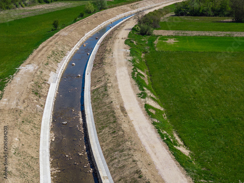 Foto Aerial view shows river channel expansion with raised embankments and reinforced waterways for flood protection near grassy areas