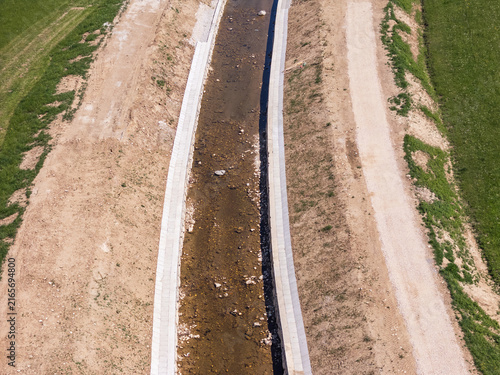 Bild auf Leinwand Aerial view shows reinforced waterways and raised embankments designed for flood protection in a rural landscape