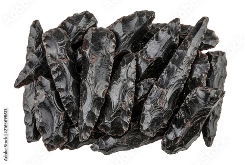 Uma coleção de pontas de flecha de obsidiana preta esculpidas à mão, dispostas sobre um fundo branco, destacando a textura vítrea e as bordas afiadas de ferramentas pré-históricas.