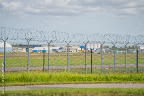 Industrial boundary protection concept featuring security chain-link fence lines and barbed wire strands at a commercial property edge