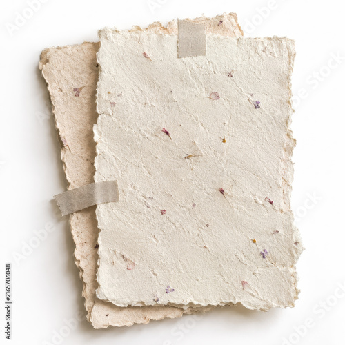 Stack of handmade paper sheets with pressed flowers and torn edges