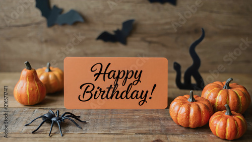 Halloween birthday party sign with pumpkins, spiders, and bats on rustic wooden table