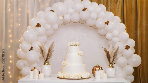 Halloween wedding cake with white roses and gold accents on rustic wooden table