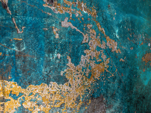 Abstract distressed turquoise wall texture with gold peeling paint close up