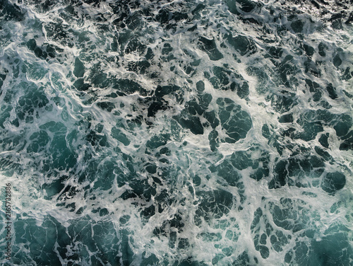 Foaming waves form an energetic abstract pattern across dark water in the North Sea, UK