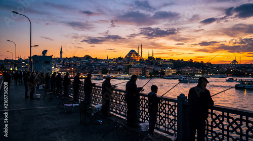 Fishermen cast their lines as the sun sets over Istanbul near the famous skyline filled with mosques