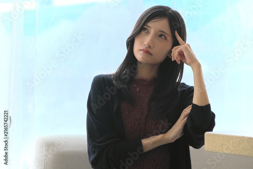 Quadro su tela 窓際で頭に指をあてて深く悩み考える若い女性（悩み・思考・ストレスイメージ）