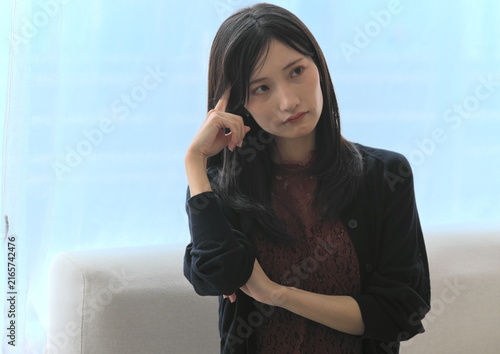 Картината върху платно 窓際で頭に指をあてて深く悩み考える若い女性（悩み・思考・ストレスイメージ）