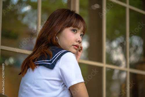 Canvas Print Japanese high school girl in traditional sailor uniform sitting thoughtfully at