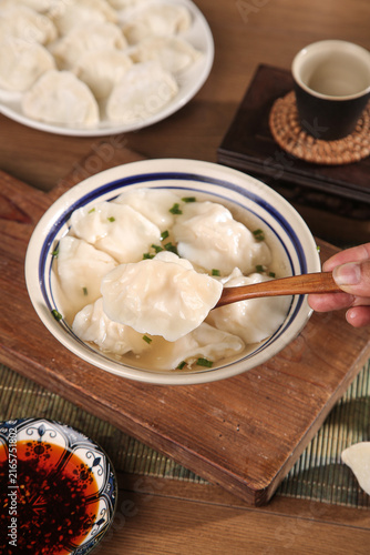 фотографія Traditional Handmade Asian Dumplings in Clear Broth with Chopsticks and Tea Serv