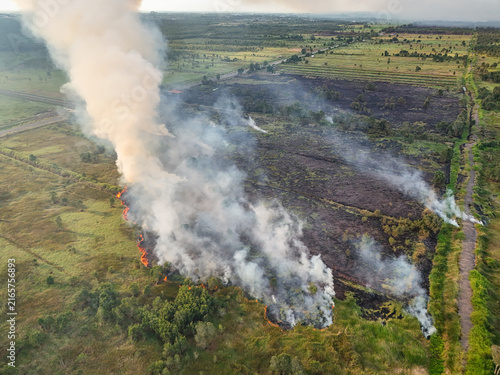 Aerial view of smoke billowing from a wildfire across a scorched landscape with patches of green vegetation in the rural countryside Banjarbaru, South Kalimantan, Indonesia.