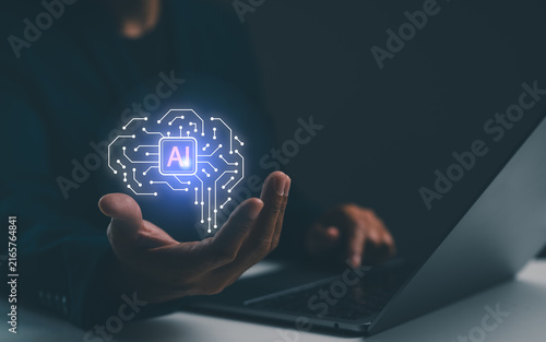 Canvas Print A person holds a glowing AI circuit hologram above their hand while working on a laptop, symbolizing artificial intelligence and technology integration