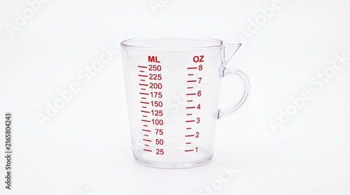 Transparent plastic kitchen measuring cup showing volume markings in milliliters and ounces for precise cooking tasks isolated on white background