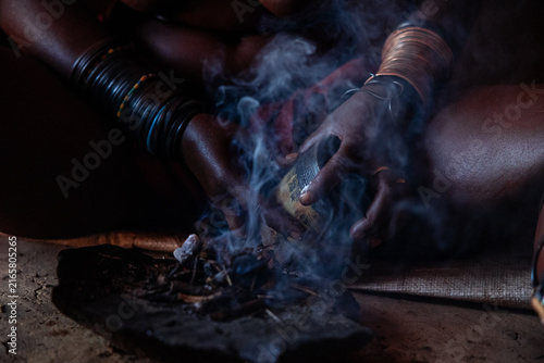 Himba woman performing traditional smoke ritual in Namibia