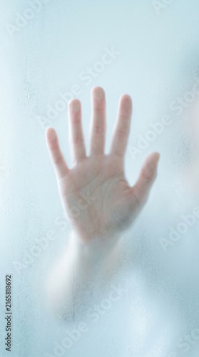 Human hand pressing against frosted white glass surface soft light close-up