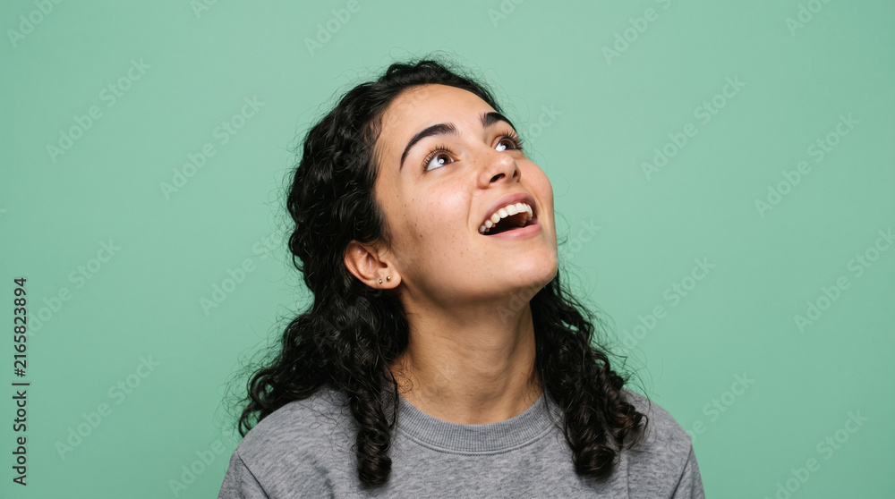 Obraz premium Happy Young Woman Looking Up with Amazement Isolated on Green Background