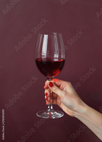 A glass of red wine in a woman’s hand on a burgundy background, an alcoholic beverage. A graphic illustration, an artificial intelligence generator, AI, an image of a neural network. Background for de