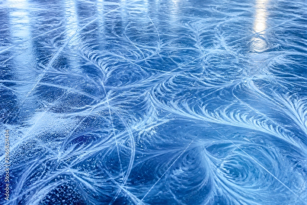 Obraz premium Frozen patterns swirl across a vibrant blue surface. Cold, delicate ice art forms elegant, flowing designs. Light glints softly off the icy texture, enhancing depth. This scene evokes quiet