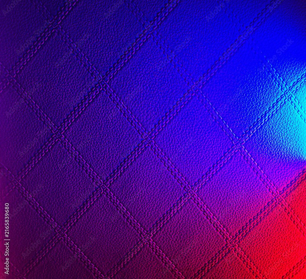 Naklejka premium Abstract quilted leather texture with vibrant blue and red neon gradient lighting effect