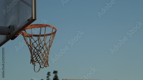 A dramatic slow motion close up video of a basketball ball missing the silhouette hoop and rim, capturing intense sports action, near miss moment, and outdoor athletic effort.