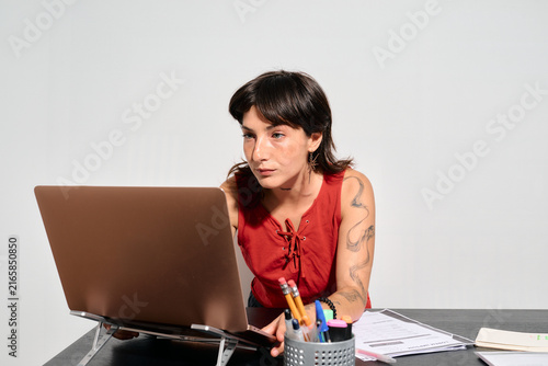 A focused woman works intently on her laptop. She concentrates deeply, her gaze fixed on the screen as she types.