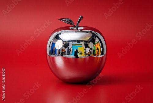 Surreal Apple with a glossy liquid chrome mirror-metallic surface on a bold red studio background futuristic reflective food art concept with copy space for commercial stock