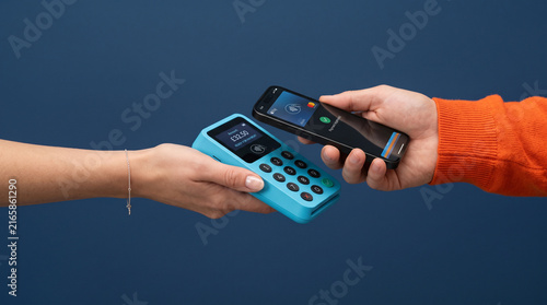 Obraz na plátně Closeup of a person making a contactless payment with a smartphone on a blue car