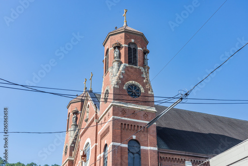 Historic Red Brick Church Tower with Cross Against Blue Sky